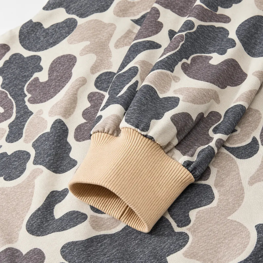 Details of the beige ribbed cuff and long camouflage sleeve, showing gathered fabric, stitching and the printed knit texture.