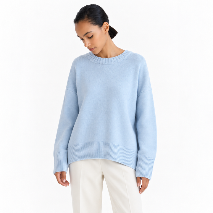 Light Blue knitted pullover on a model against white, with a crew neckline, dropped shoulders, long sleeves and ribbed edges.