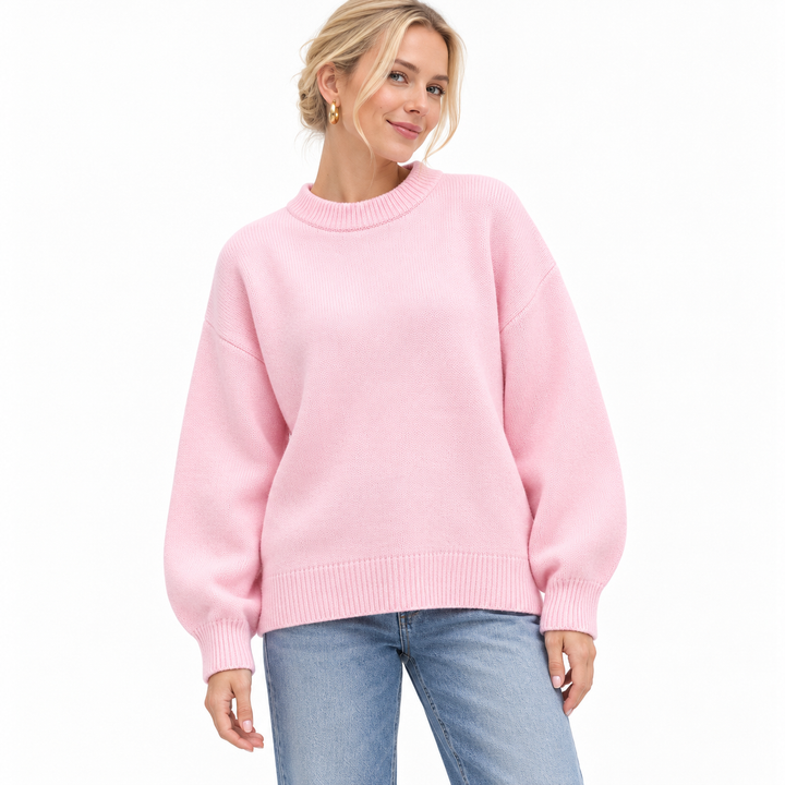 Pink knitted pullover shown on a model against white, with a crew neckline, dropped shoulders, long sleeves and ribbed edges.