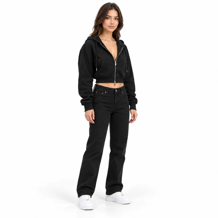 Black cropped hooded sweatshirt on a model shown full body in a three-quarter front view with black jeans and white sneakers.