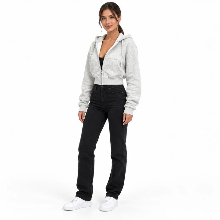 Heather gray short hooded sweatshirt on a full-body model in a slight three-quarter view with black jeans and white sneakers.