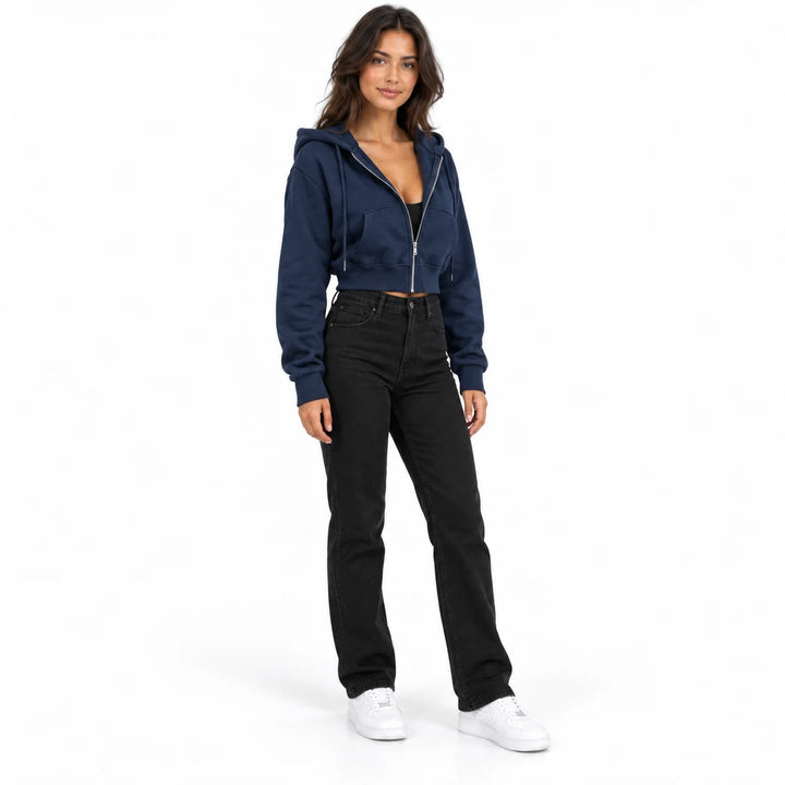 Navy blue cropped hoodie on an adult model shown full body in a three-quarter front view with black jeans and white sneakers.