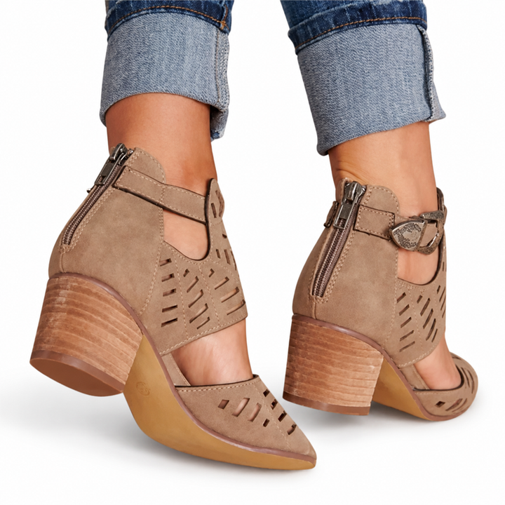 Rear view of brown cutout sandals with back zips, side buckles and broad heels, worn with cuffed jeans on a white background.