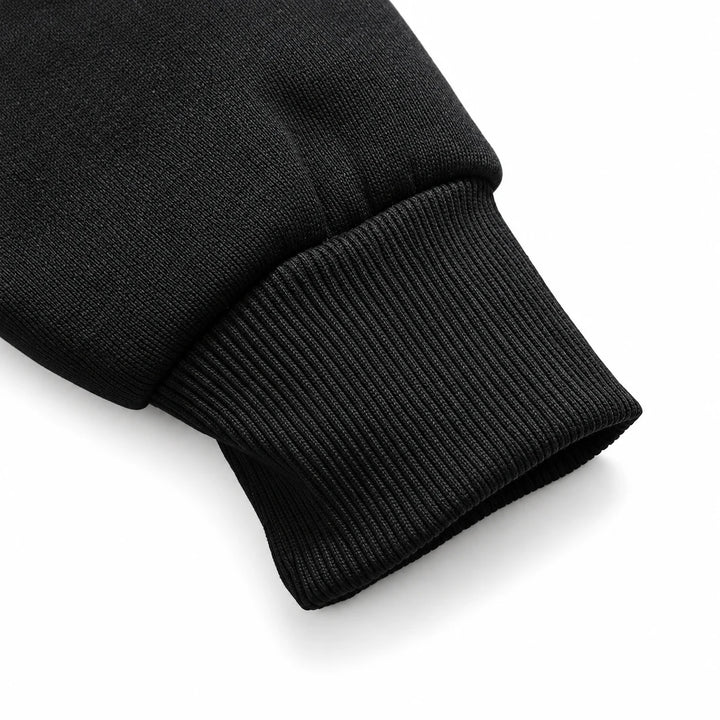 Close-up of a black ribbed hoodie cuff and sleeve seam.