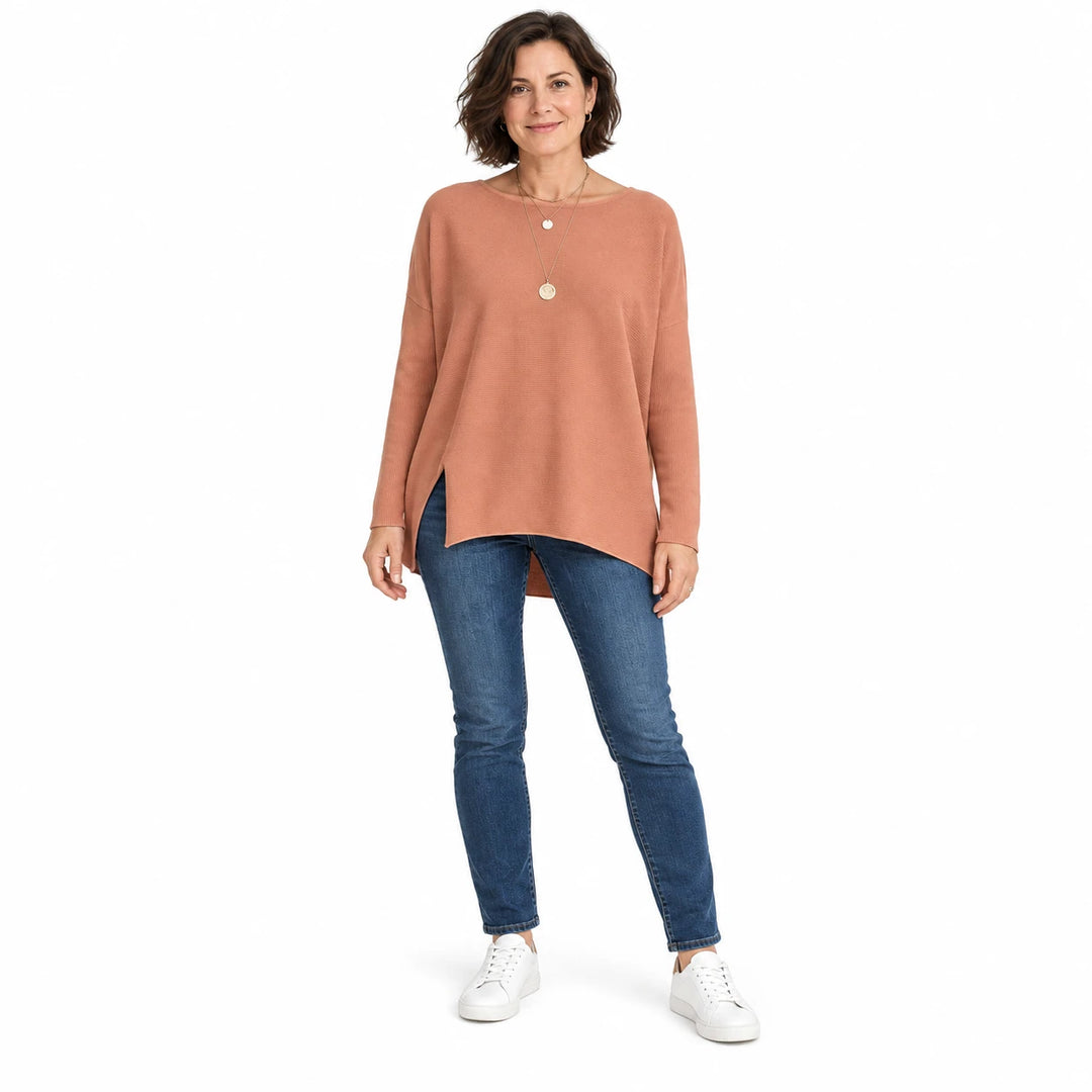 Short-haired adult woman wearing the Amber batwing sleeve pullover, in a full-body front view against a plain white backdrop.