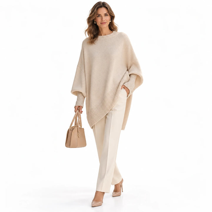 Adult woman wearing the Apricot 2 chunky knit sweater with a draped hem, in a full-body studio view against a white backdrop.