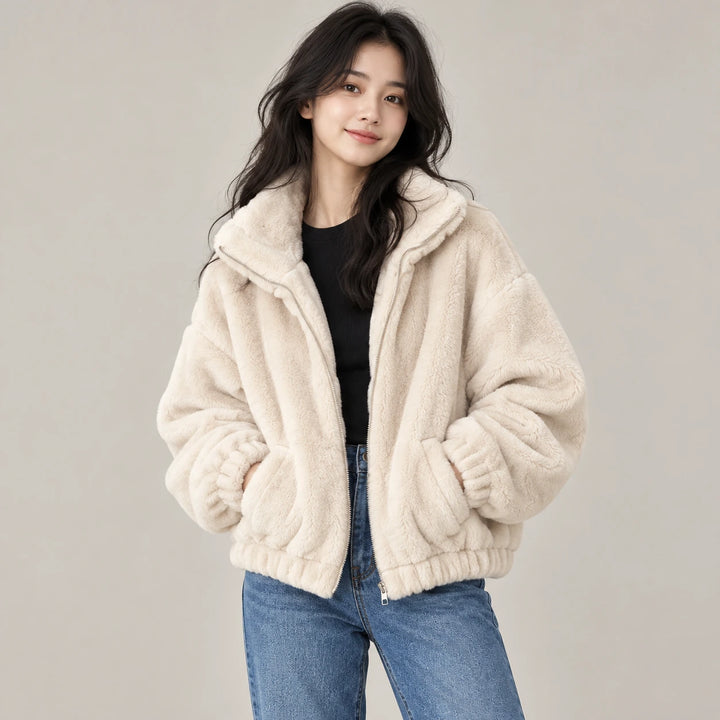 Model wearing the beige plush jacket with a black top and blue jeans, showing the collar, zipper and front pockets in studio.