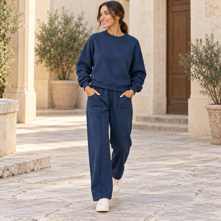 Navy blue sweatshirt and wide-leg trouser set worn by a full-length model walking in a courtyard
