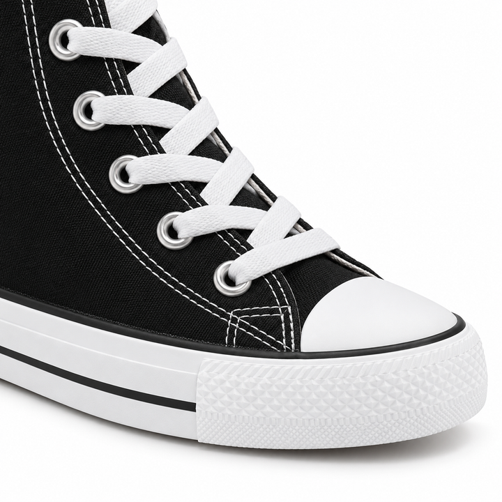 Close-up of black high-top sneaker white laces, silver eyelets, white stitching and rubber toe