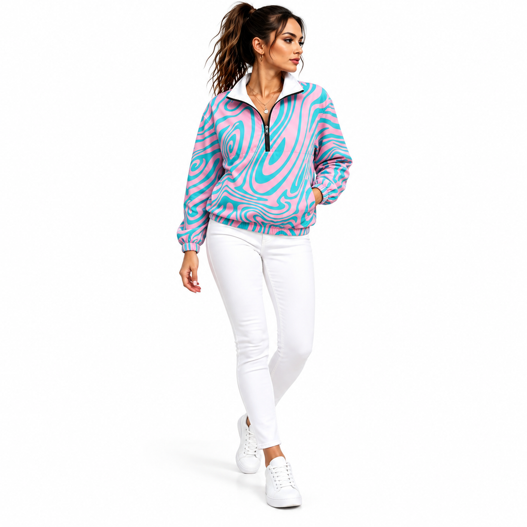 Woman wearing a pink and cyan swirl printed jacket with white jeans and white sneakers shown walking in a plain white studio.