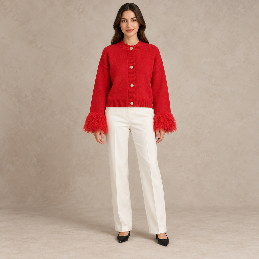 Full-body model wearing a red cardigan with feather cuffs and four gold-tone buttons in a taupe studio