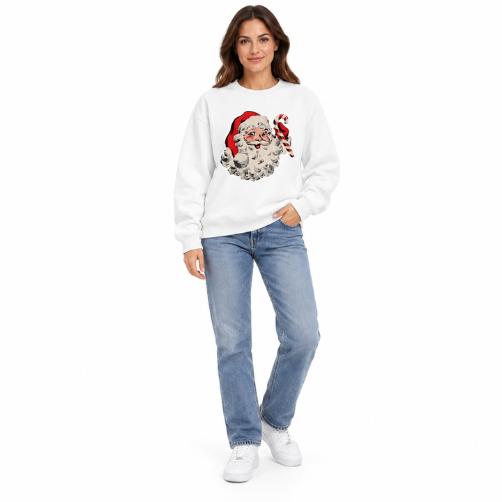 Full-length woman in a white Santa sweatshirt with a candy cane print, blue jeans &amp; white sneakers on a white studio backdrop