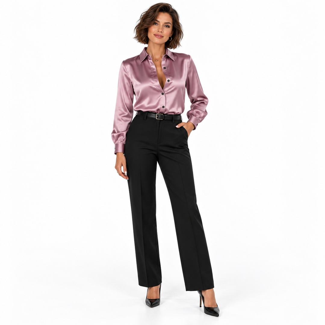 Brunette model wearing a muted pink collared shirt with black trousers and black shoes, shown full length on a white setting.
