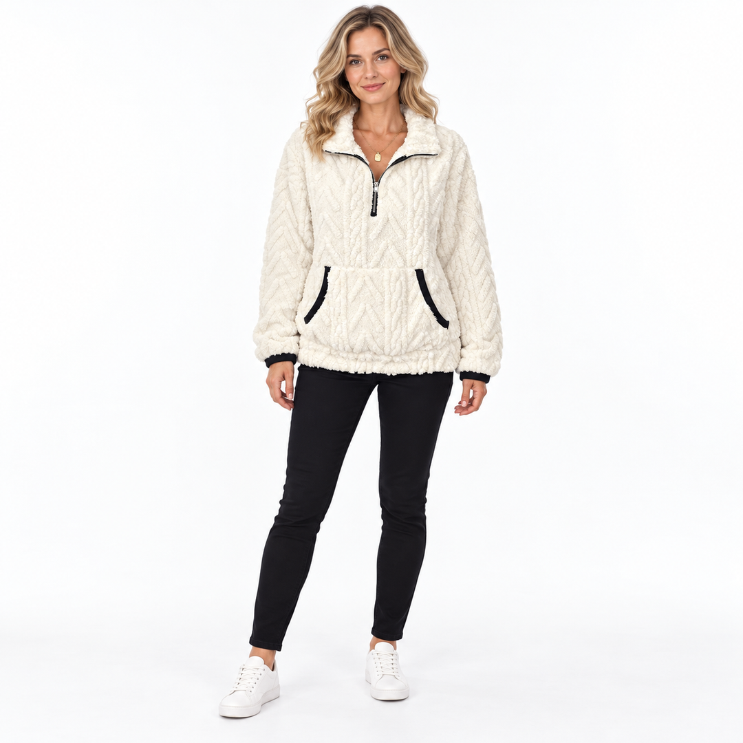 White sherpa sweatshirt on a full-body blonde model with black trousers and white sneakers, showing a zip collar and pockets.