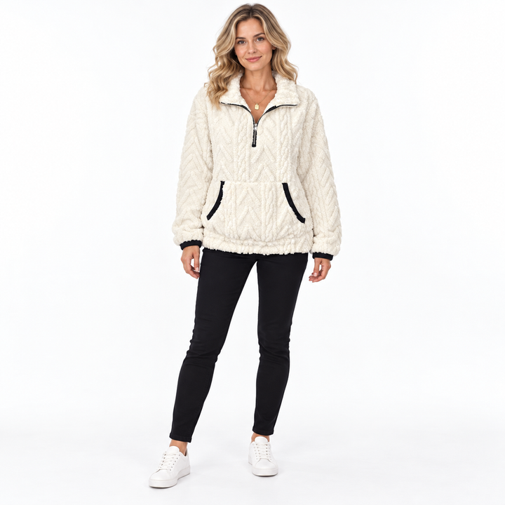 White sherpa sweatshirt on a full-body blonde model with black trousers and white sneakers, showing a zip collar and pockets.