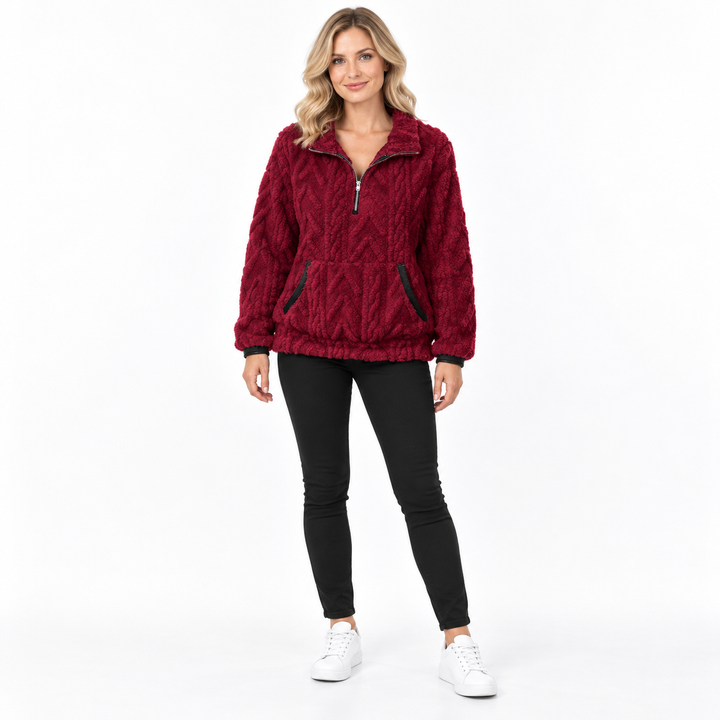 Burgundy textured zip-neck pullover on a blonde model in black trousers and white sneakers, showing collar and front pockets.