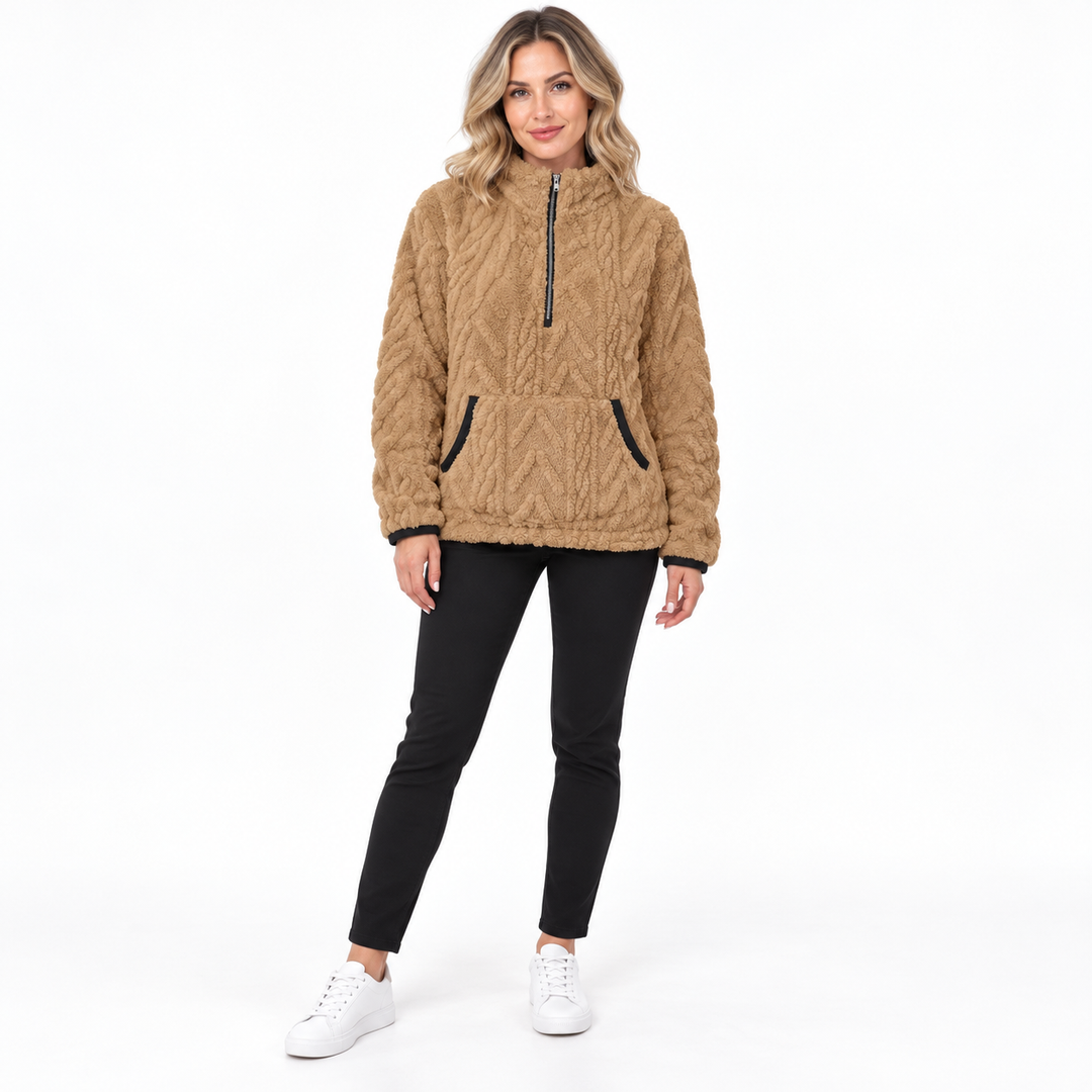 Khaki textured zip-neck pullover on a blonde model in black trousers and white sneakers, showing a zip collar and black trim.
