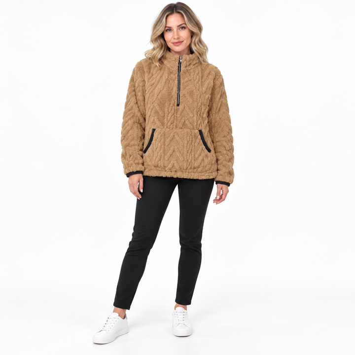 Khaki textured zip-neck pullover on a blonde model in black trousers and white sneakers, showing a zip collar and black trim.