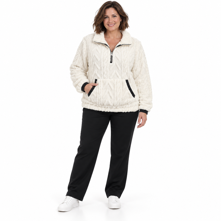 Curvy brunette woman in the white textured zip-neck pullover, black trousers and white shoes, photographed in a white studio.