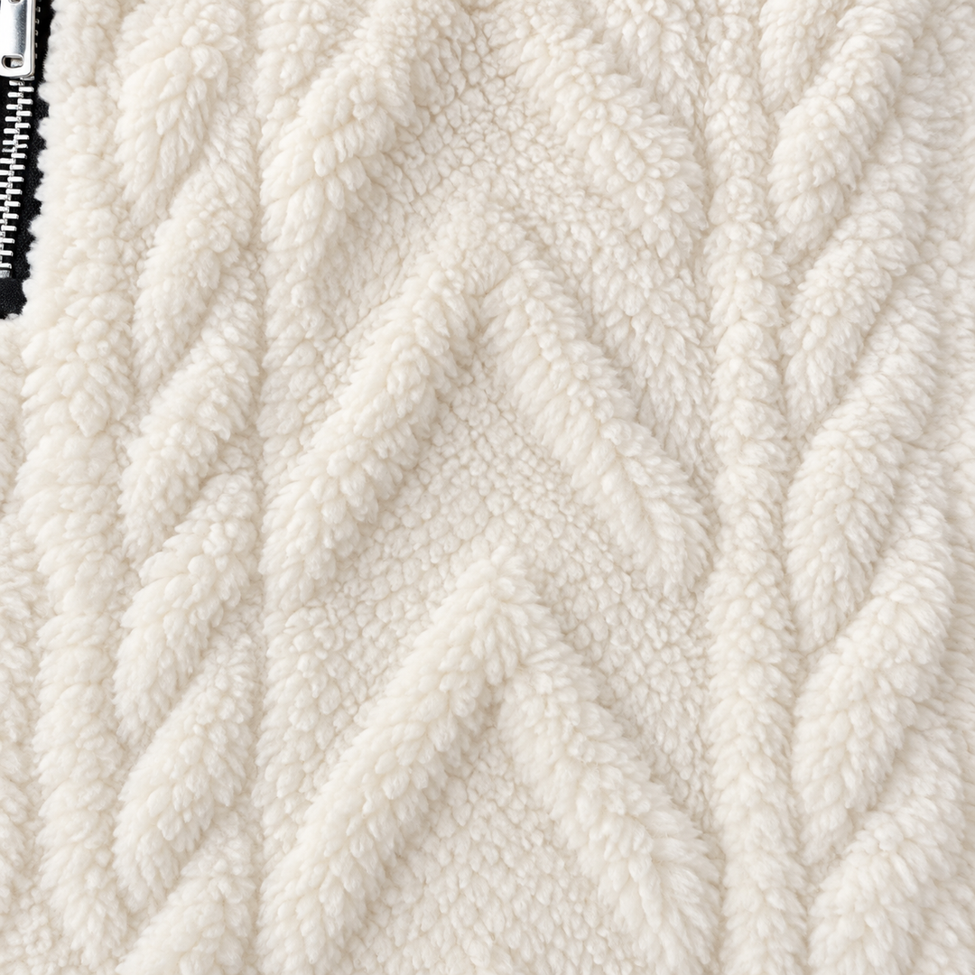 Close-up of white raised cable-pattern sherpa texture with the black zipper and metal teeth visible along the left-hand edge.