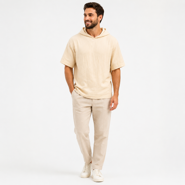 Man wearing an apricot short sleeve pullover hoodie, full-body front view on a white studio background.