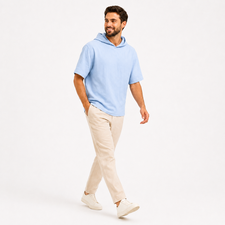 Man wearing a sky blue short sleeve pullover hoodie in a full-body walking pose on white.