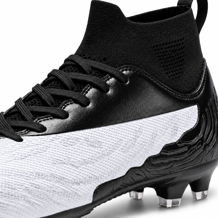 Close-up of white and black soccer cleat showing textured upper, black laces, knit ankle collar and sculpted heel details.