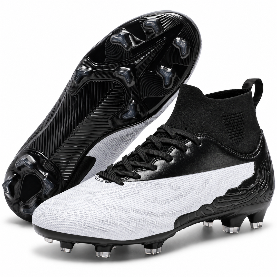 White and black soccer cleats with the outsole facing camera, highlighting the molded sole pattern and outdoor stud arrangement.