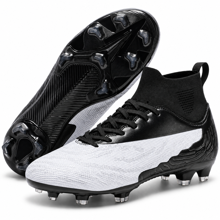 White and black soccer cleats with the outsole facing camera, highlighting the molded sole pattern and outdoor stud arrangement.