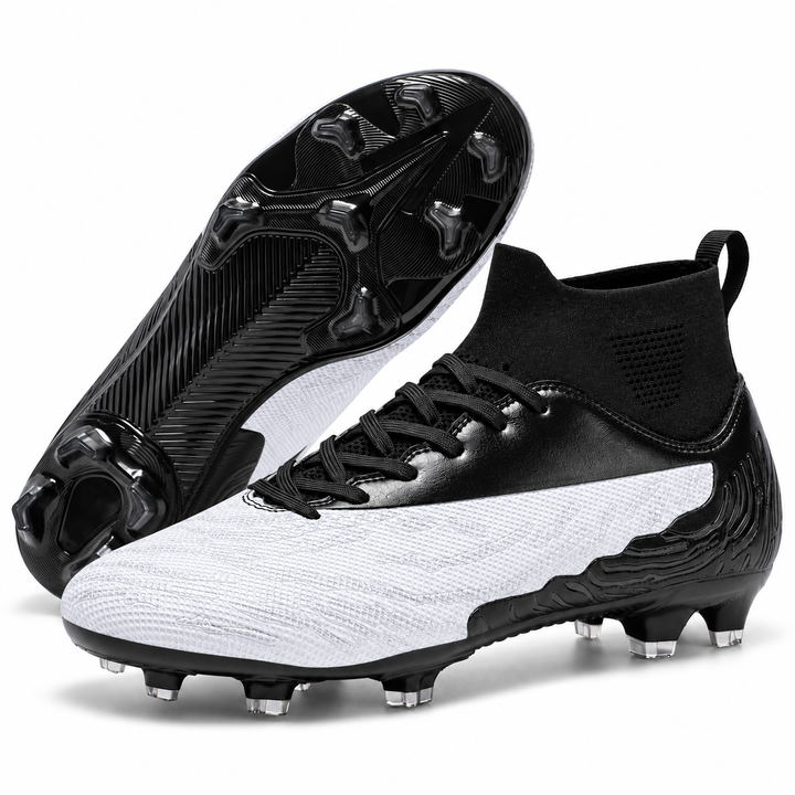 White and black soccer cleats shown as a pair with one outsole visible, highlighting the molded stud layout for outdoor play.