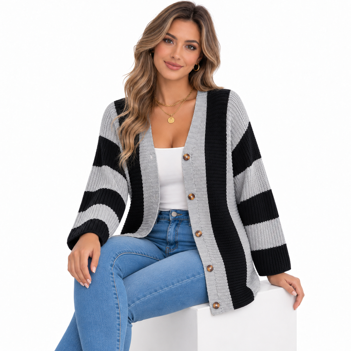 Grey and black striped cardigan styled on a seated model with blue jeans on a clean white studio background