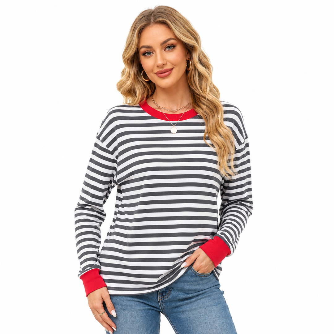 Striped long sleeve top for women in gray and white stripes with red neckline and cuffs, styled with blue jeans on white set.