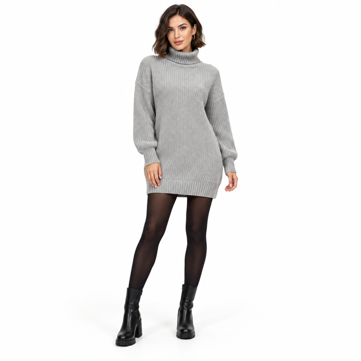 Another adult model wearing the gray knit dress with a short brunette hairstyle, black tights and ankle boots on a white set.