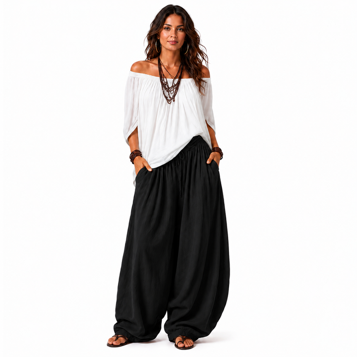 Woman wearing a white off-shoulder top and black gathered pants, front view on a clean white studio background.