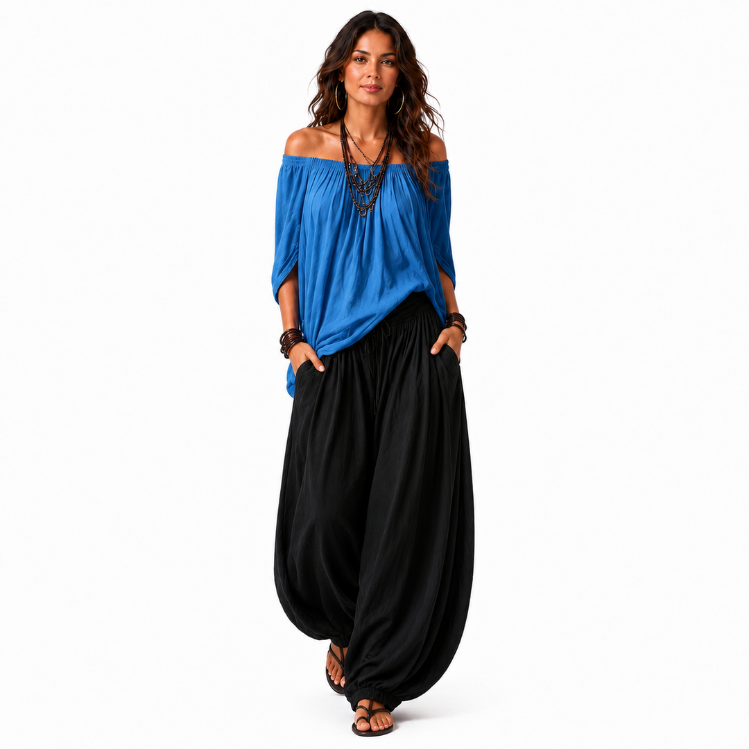 Woman wearing a bright blue off-shoulder top and black gathered pants, full outfit shown on a white background.