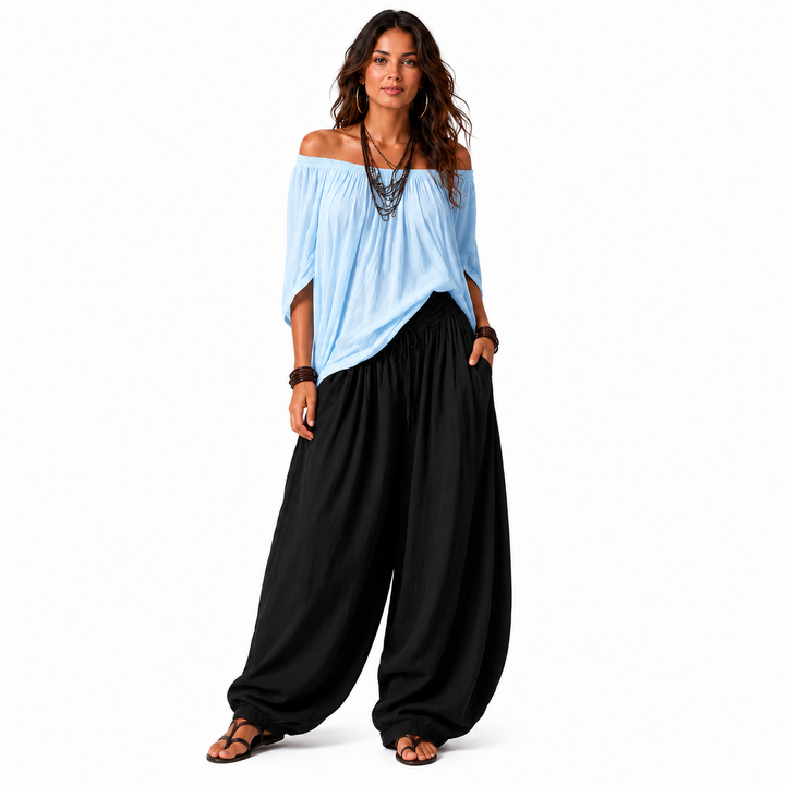 Woman wearing a light blue off-shoulder top and black gathered pants, full outfit shown on a white background.