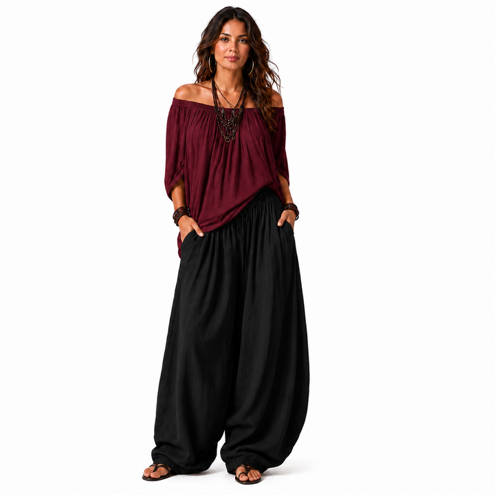 Woman wearing a wine red off-shoulder top and black gathered pants, full outfit shown on a white background.