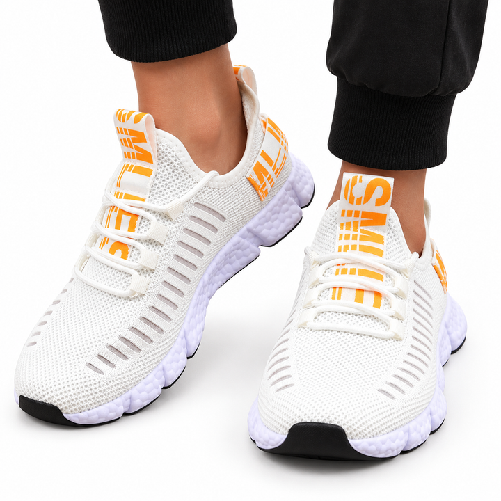 Casual sneakers in ivory white with orange accents, mesh upper, round toe, cross-strap lacing and segmented white sole.