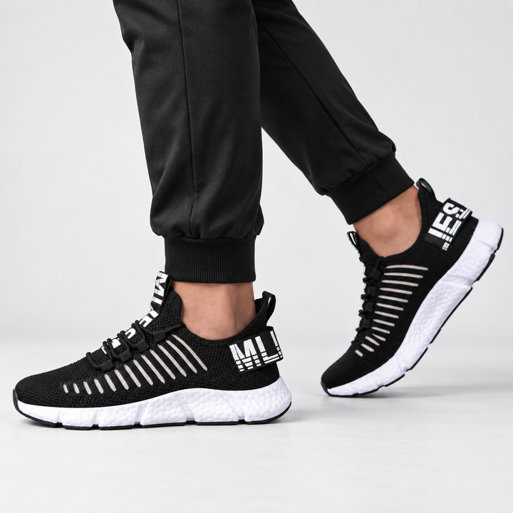 Midnight black casual sneakers shown from the side on a model, highlighting the low-top silhouette and segmented white sole.