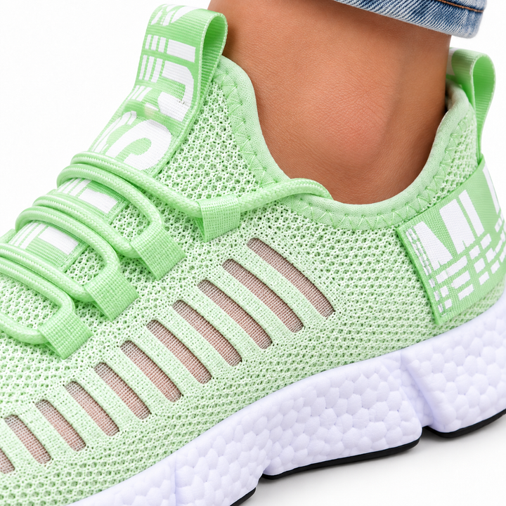 Mint green casual sneaker macro view showing mesh texture, stitched edge, cross-strap lacing and the segmented white sole detail.