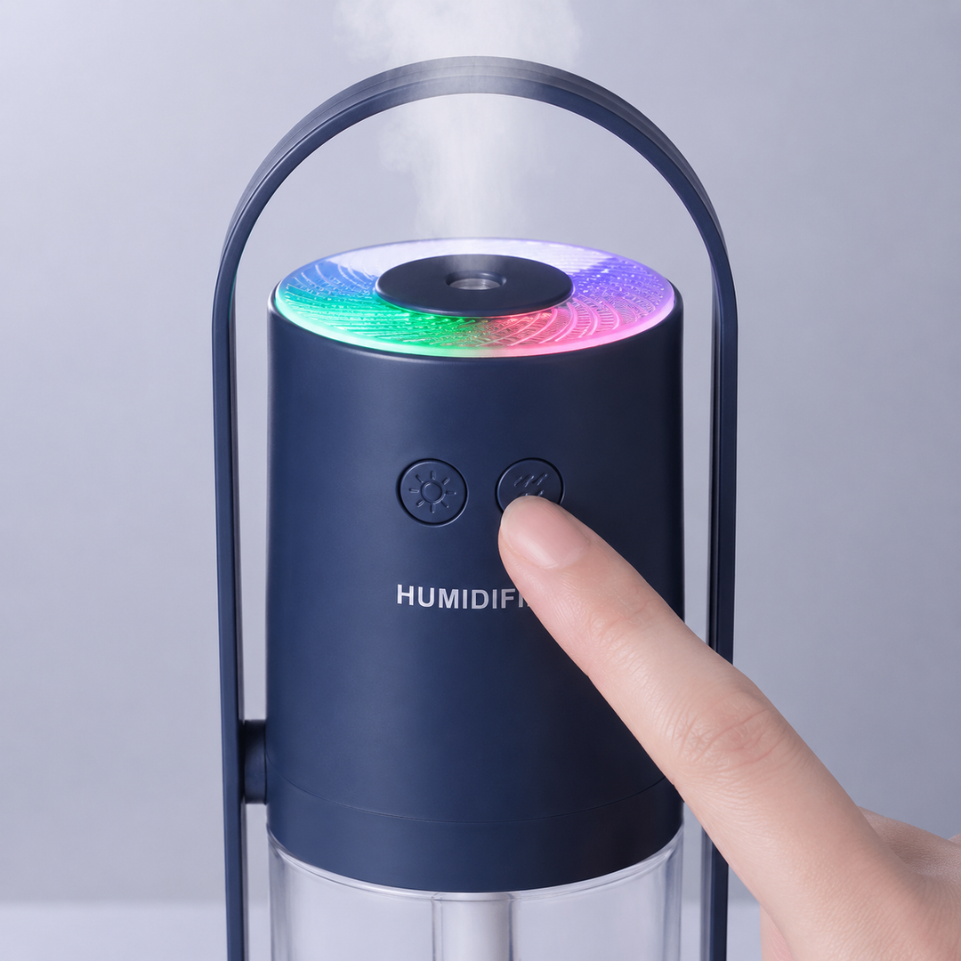 Close view of dark blue controls, hand pressing mist button, active color lamp ring and fine mist rising from the top nozzle.