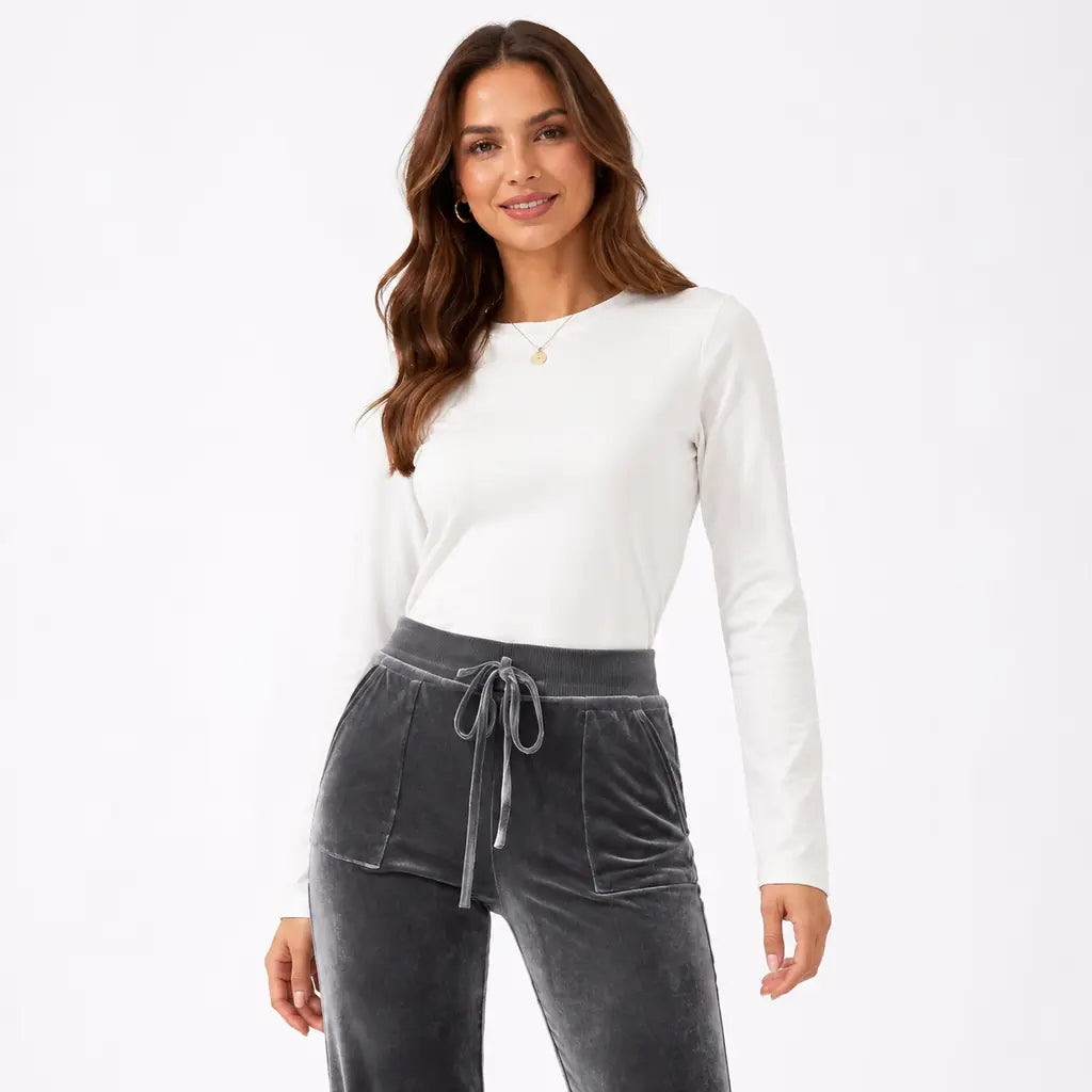Close-up front view of dark gray velvet flare pants with model face showing the high waistband, drawstring and patch pockets.