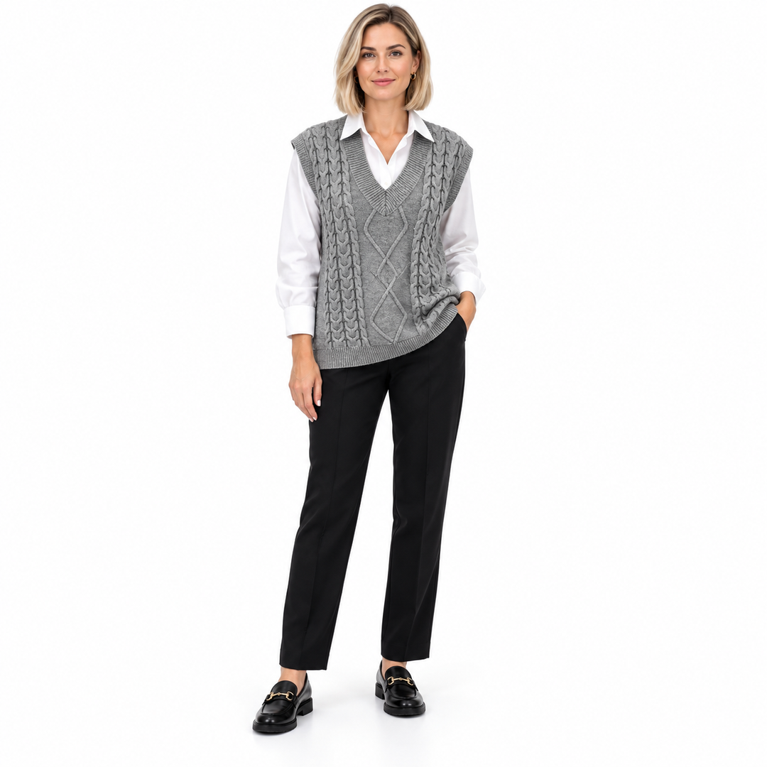 Grey cable knit vest from the front on a full-length model with a white shirt, black trousers and loafers on a white backdrop