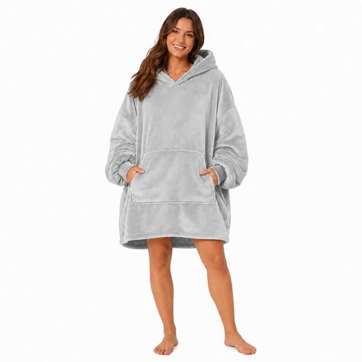 Dark gray wearable blanket hoodie with hood and large front pocket modeled by a woman on a clean white studio background.