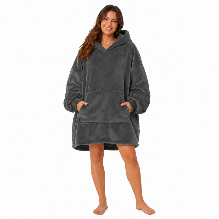 Pink wearable blanket hoodie with hood and large front pocket modeled by a woman on a clean white studio background.