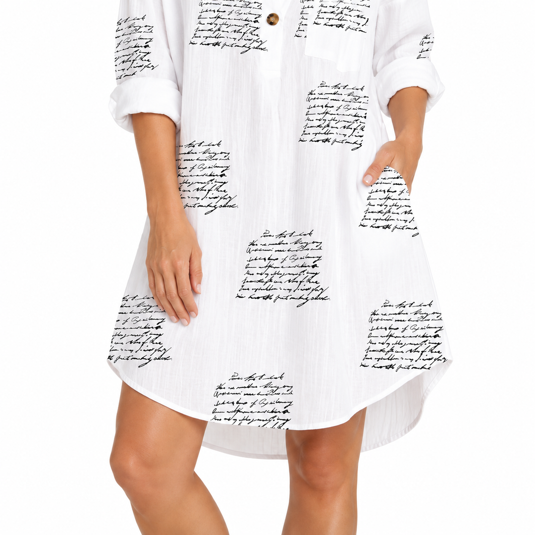Close-up of curved hem and black script print, showing garment drape, lower edge and stitching detail on the printed dress