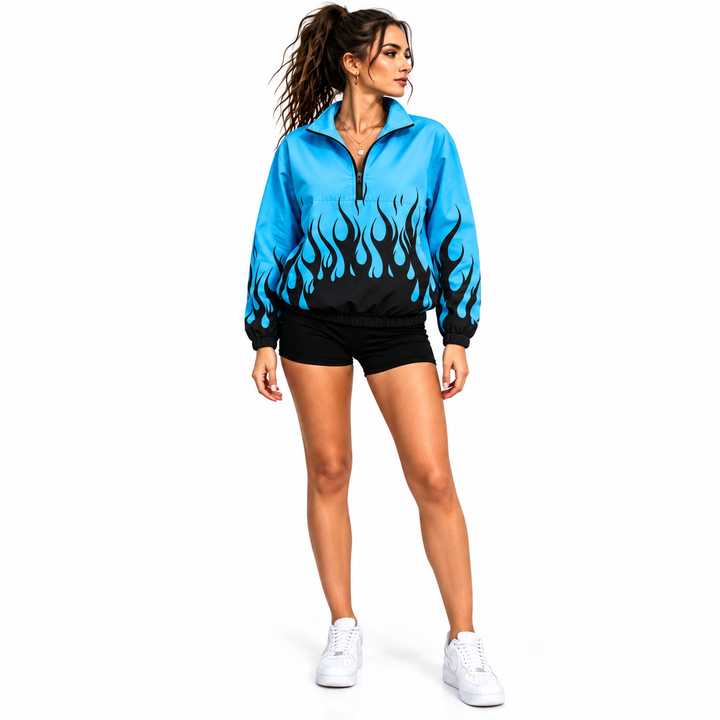 Front view of woman wearing a blue and dark flame pullover jacket with stand collar and half zipper on white studio backdrop.