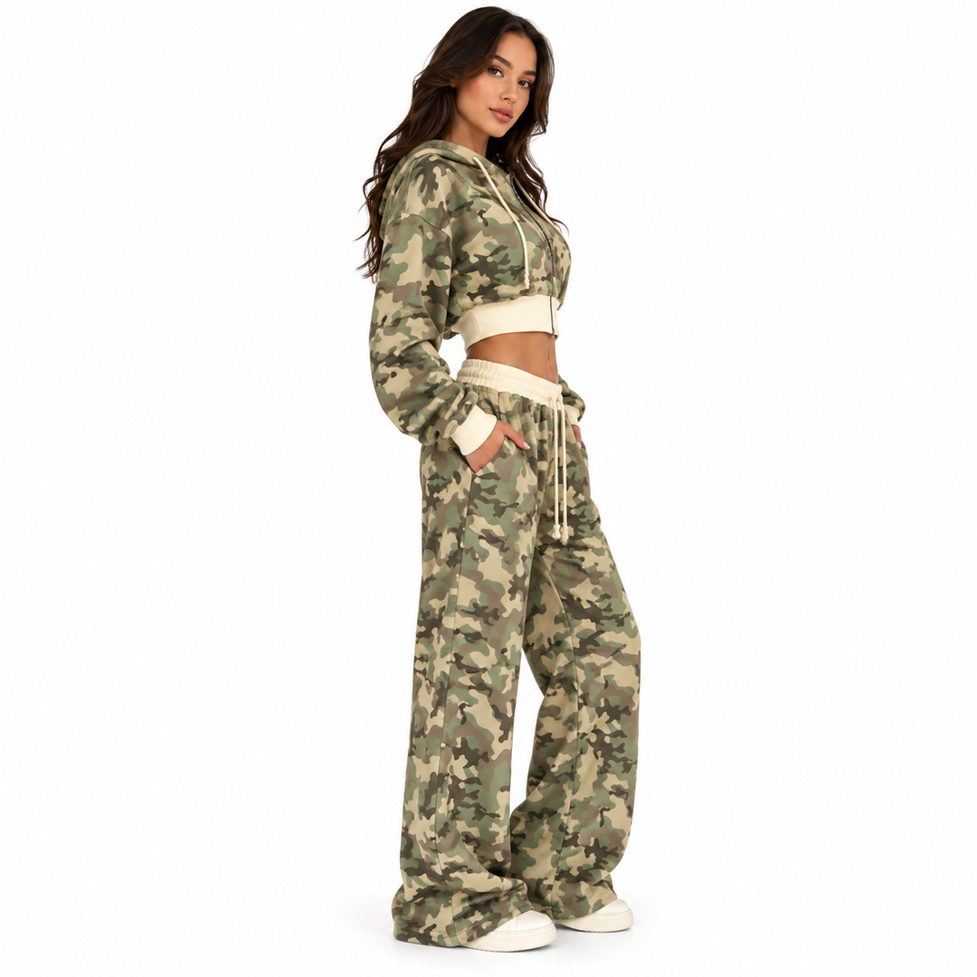 Woman wearing the camouflage two-piece tracksuit in a side studio pose showing the cropped hoodie and wide-leg pants profile.