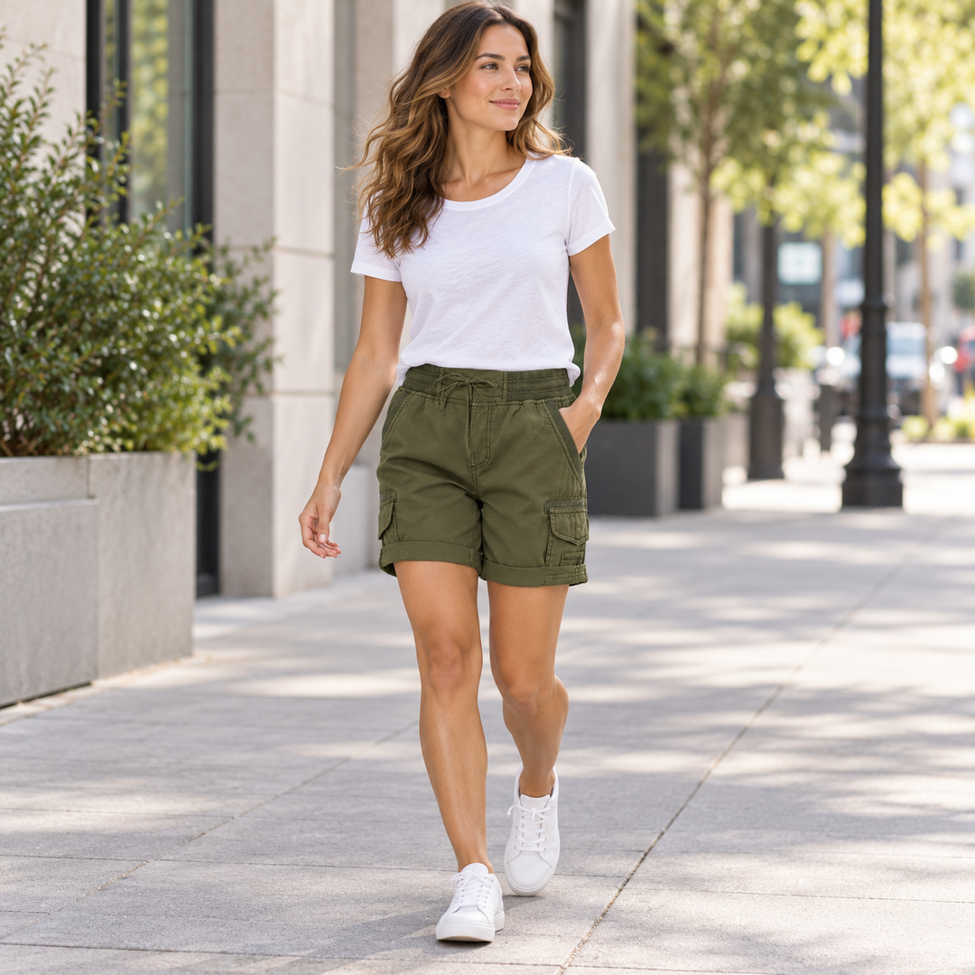 Woman wearing army green cargo shorts with a white T-shirt on a city walk.