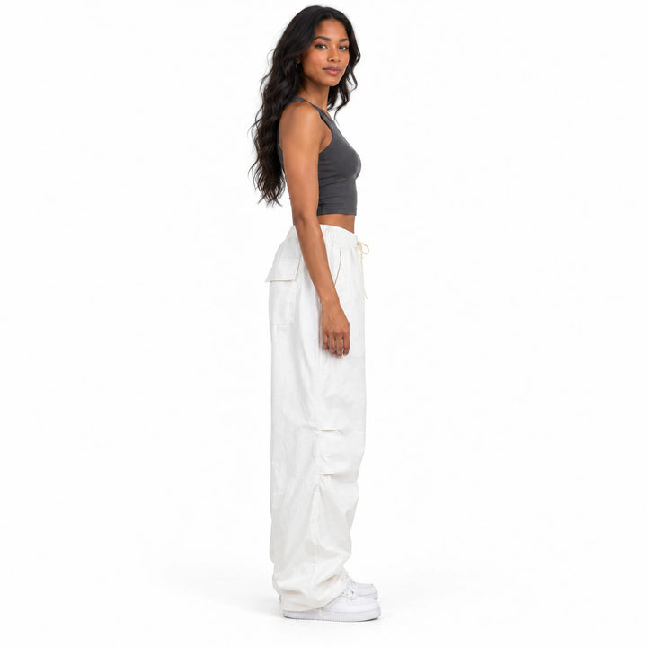 Side view of the white cargo pants on a model, showing the relaxed full-length legs, side seams and the outline of the waist.
